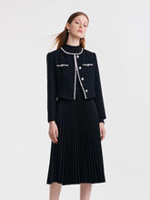 A woman wears a black vintage suit.